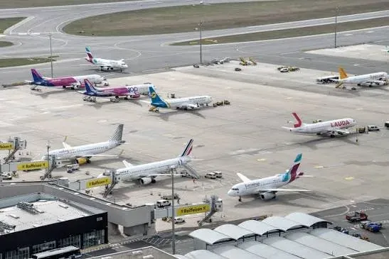 An aerial view of many airliners parked across a busy airport apron.
