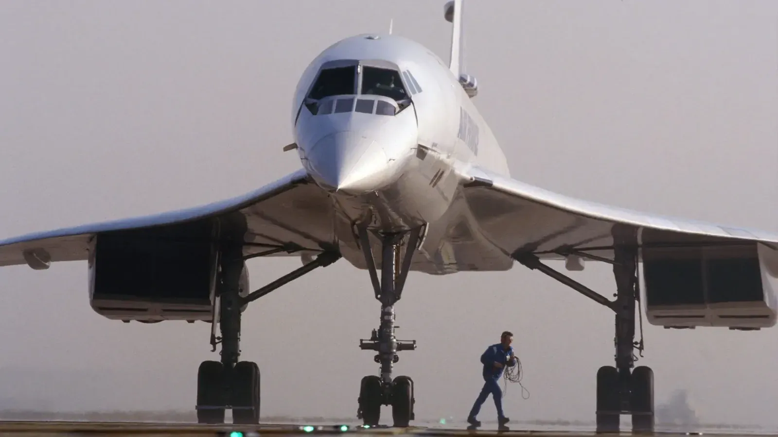 An Air France Concorde on the tarmac, its droop nose lowered, a ground crew member walking beneath it.