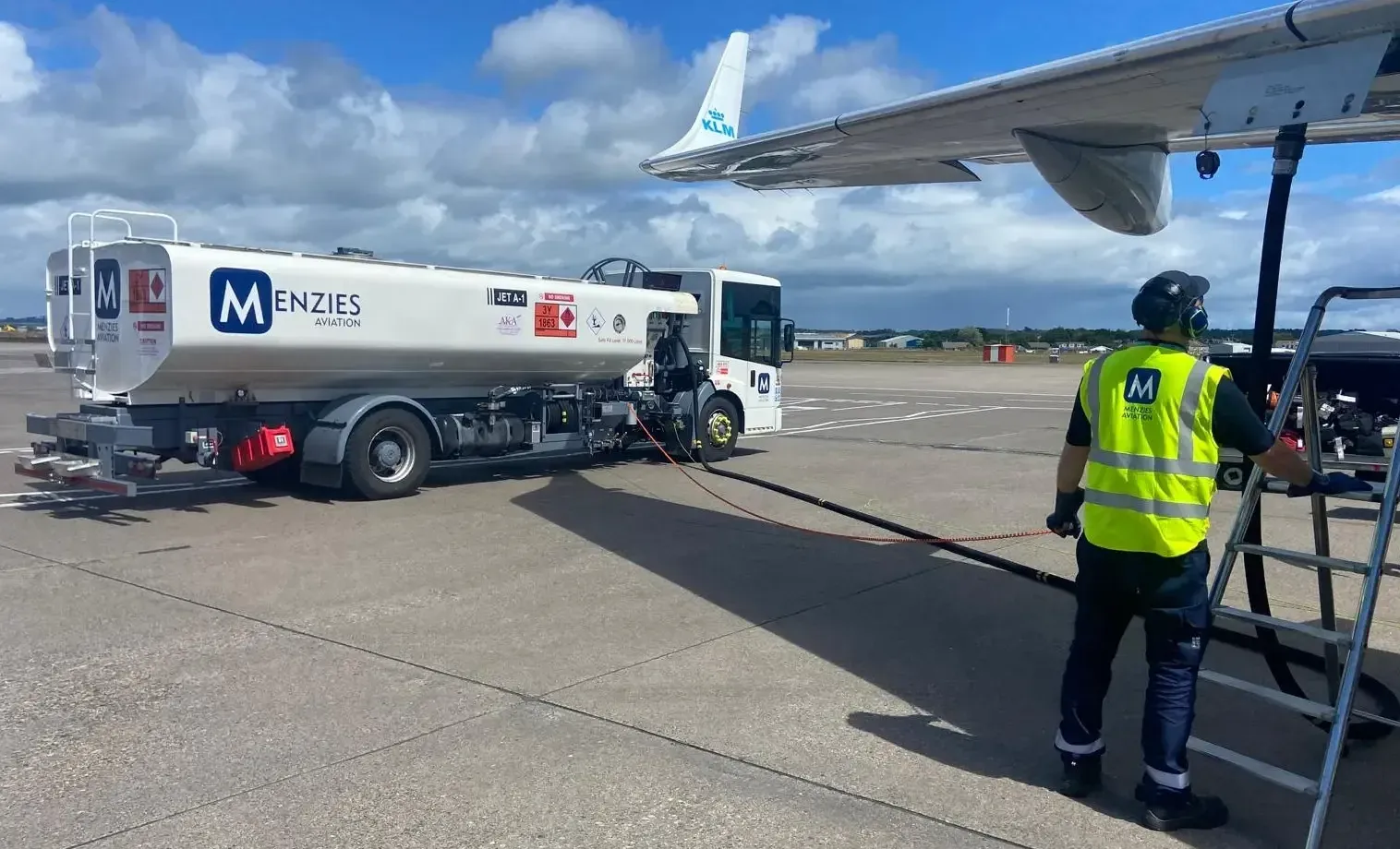 A jet fuel tanker refuelling an airliner on the airport apron.