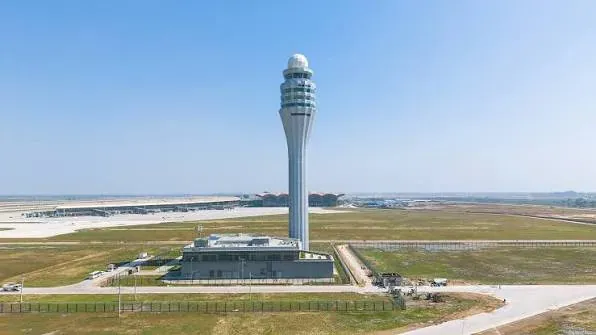 An air traffic control tower rising over an airport in clear daylight.
