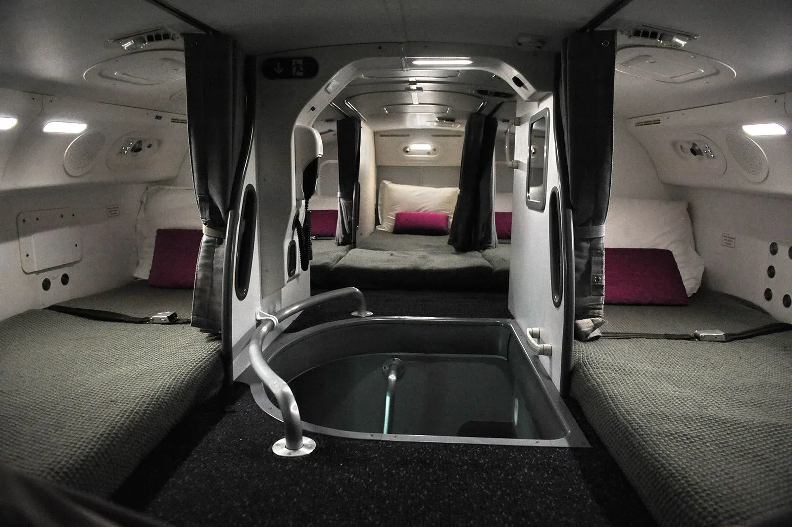 A hidden crew rest compartment inside an airliner, with bunks and pillows tucked above the cabin.