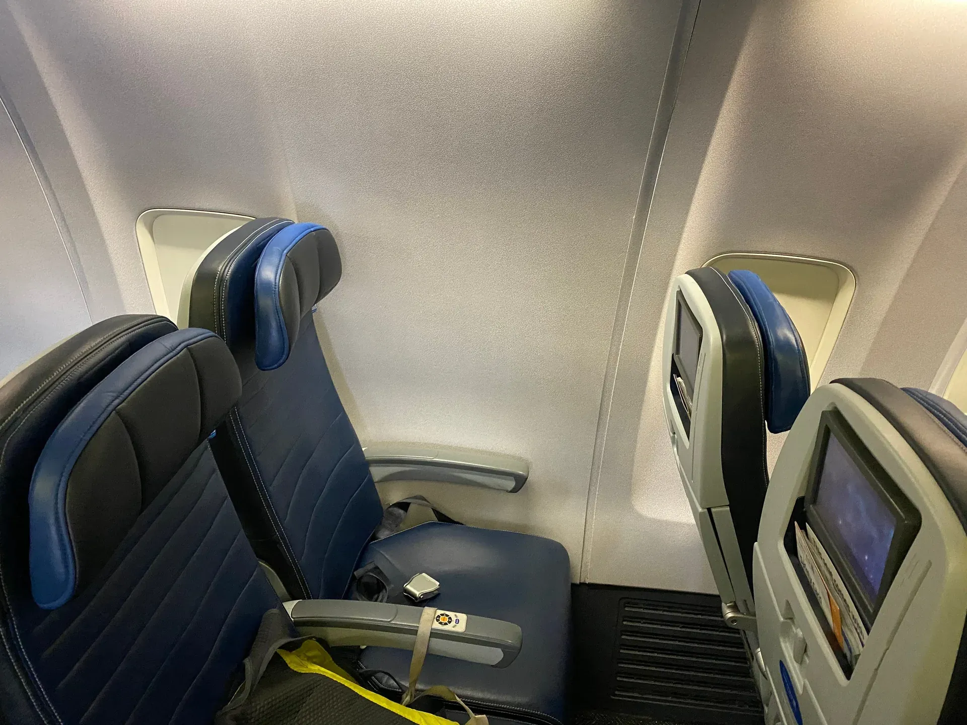 A cabin window seat facing a blank wall where the window should be, next to seats with normal windows